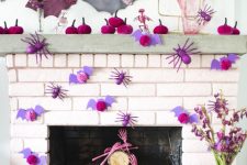 a bright and chic Halloween mantel with fuchsia velvet pumpkins, purple bats and spiders, pink skull hands and pastel bats