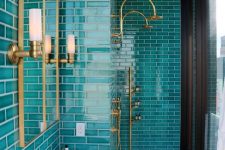 a bright bathroom clad with turquoise tiles, with gold fixtures and a mirror in a gold frame is a bold and catchy space