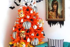 a color block Halloween tree in orange and yellow, with striped oversized ornaments, black ornaments and mini ghosts and bats over it