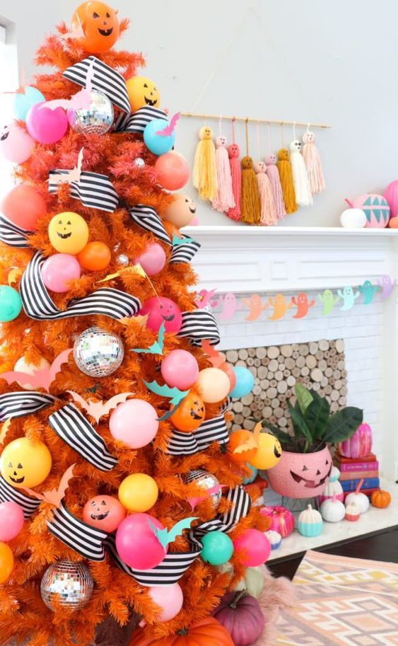 a colorful Halloween tree in orange, with pastel ornaments and balloons, striped garlands and jack o lanterns