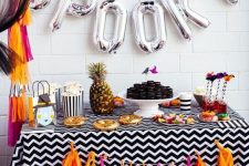 a colorful candy bar with a bright tassel garland and silver letter balloons plus a pineapple for a tropical feel