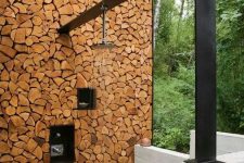 a contemporary rustic outdoor shower with a firewood wall and a dark metal panel