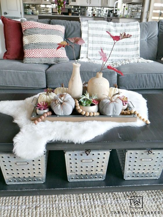 a fall centerpiece with wooden beads, natural and fabric pumpkins and red fall leaves in vases