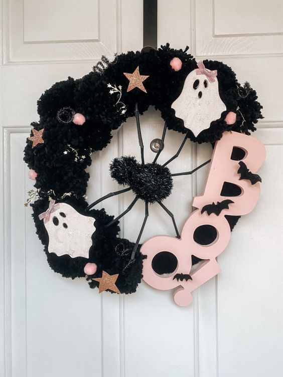 a fun Halloween wreath covered with black fabric, with mini ghosts, stars, beads and pink letters plus a giant spider in the center