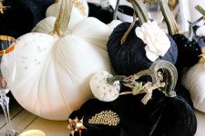 a glam Halloween centerpiece of black and white pumpkins with beads and studs, gold candleholders and chargers