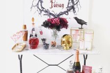 a glam cocktail nook with a gold skull, a crow, a bold floral arrangement, cages and a gold mini table