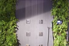 a lovely contemporary shower space with living walls, rocks on the floor and rain shower heads with colored lights