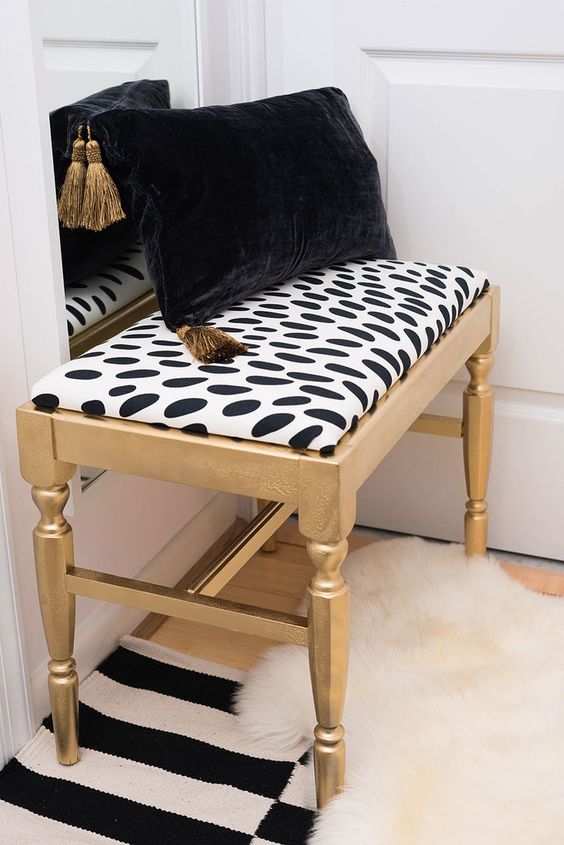 a lovely gold bench with a spotted seat, a black and gold pillow is a pretty idea for any modern glam room