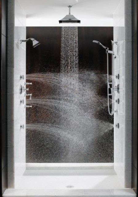 a luxurious massage shower space clad with black and white tiles, with rain shower heads on the ceiling and walls