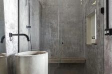 a minimalist industrial bathroom fully clad with concrete, a free-standing sink, black pipes and potted greenery