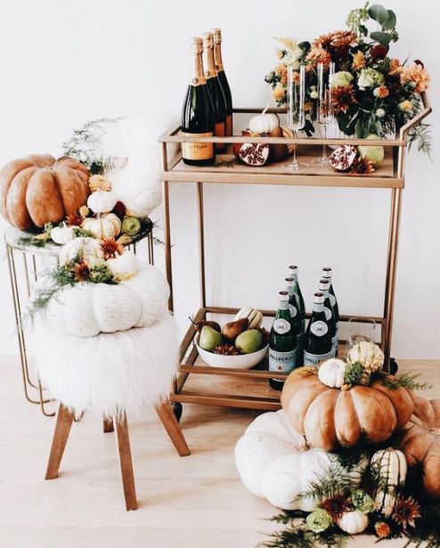 a modern Thanksgiving bar cart with a gilded cart, fall blooms, heirloom pumpkins and faux fur