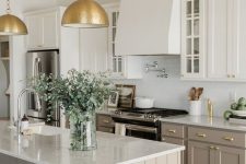 a modern farmhouse kitchen with white and taupe cabinets, white tiles and countertops, gold metal pendant lamps and gold fixtures