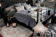 a moody bedroom with a black accent wall, a black metal bed with lights, potted plants and candles
