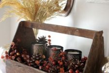 a natural fall centerpiece of a toolbox with berries, cinnamon bark, candleholders and a wheat arrangement