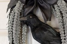 a refined Halloween wreath of black vine, hanging whitewashed blooms, a black black silk bow and a blackbird is classics for Halloween