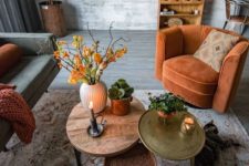 a rust-colored chair, blanket, bright coffee tables and bold orange blooms add fall coloring to the living room