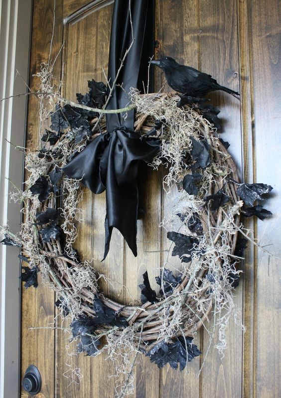 a shabby Halloween wreath of vine, hay, black leaves and a blackbird on top plus a black silk bow is amazing