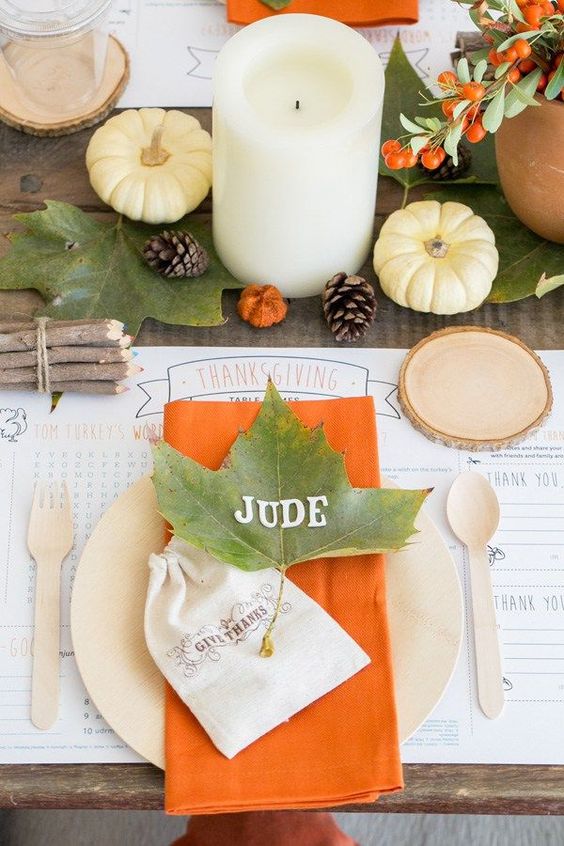 a simple Thanksgiving table with fall leaves, berries, pumpkins, pillar candles and touches of orange