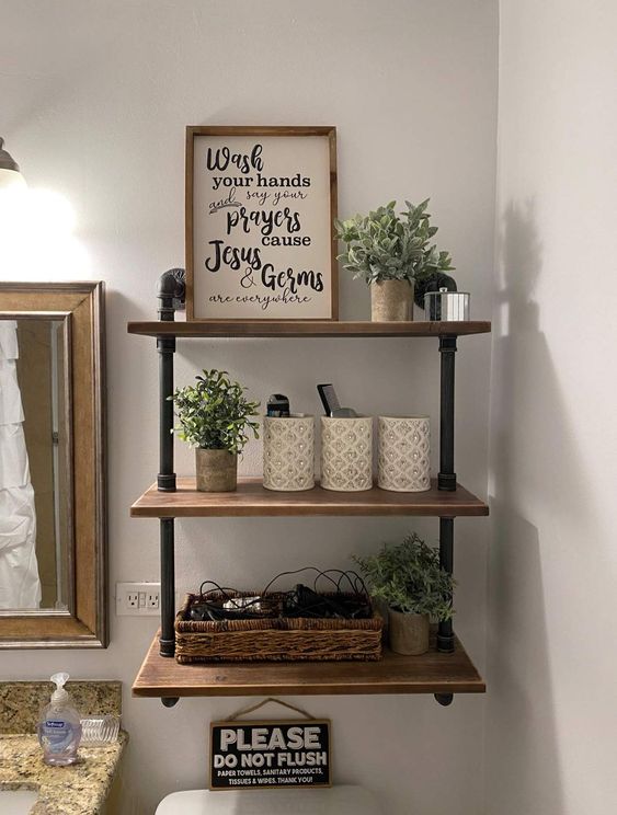a small and cool black piping and stained wood wall mounted shelf with potted greenery, baskets and a sign is amazing
