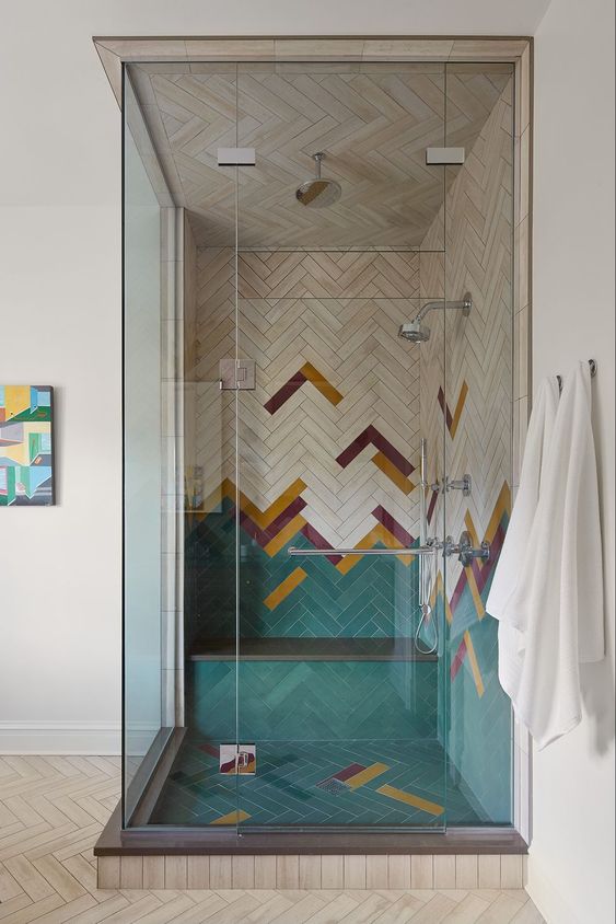 a super creative colorful shower space done with green, burgundy, mustard chevron tiles and enclosed in glass is amazing