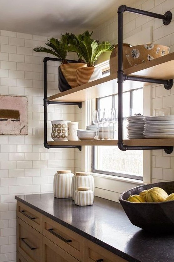 a wall-mounted shelving unit of black pipes and wood is a stylish idea for adding an industrial touch to the kitchen