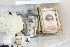 a white floral arrangement with spiders, jars with glam striped and crown mugs and a cool artwork in a refined frame
