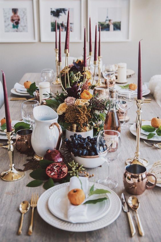 an elegant modern Thanksgiving with tall burgundy candles, copper and gold touches and white porcelain plus blooms