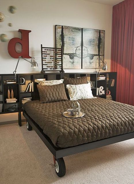 an industrial bedroom with a large metal shelf and a metal bed on casters, red curtains and some decor on the wall