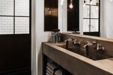 an industrial chic bathroom with a glazed shower space, a concrete vanity with a double sink, a rough wooden floor, exposed pipes and bulbs