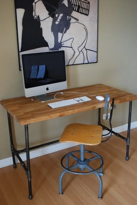 an industrial desk of exposed pipes and a stained wood desktop, a matching industrial stool for a vintage-inspired working space