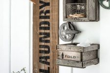 an industrial laundry space with a reclaimed wood shelf with pipes and clothes hangers, crates for storage and metal wheels