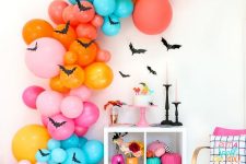 an oversized colorful balloon garland with bats, bright books and pumpkins for Halloween decor