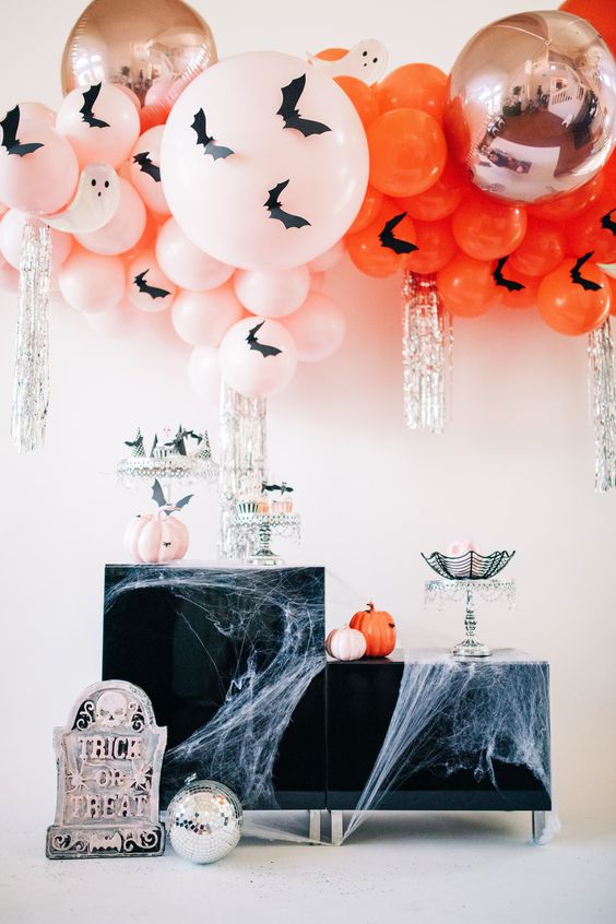 blush and orange balloons with bats, matching pumpkins and silver fringe plus spiderwebs and a gravestone