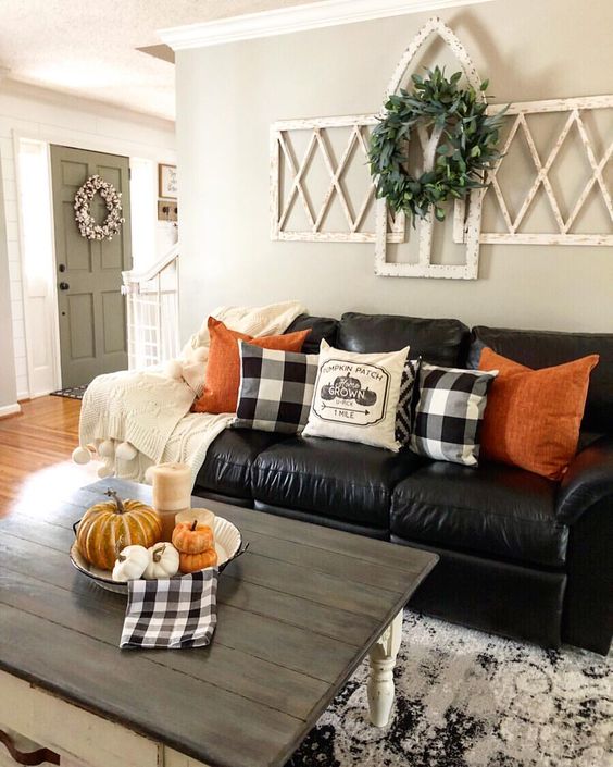 bright orange pillows and a bowl with pumpkins and candles are added for a fall touch