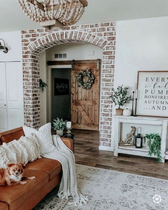 neutral pumpkins, ggreenery arrangements and cozy white blankets and pillows for a welcoming fall feel in the space