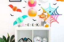super bright and fun Halloween styling with color block half pumpkins, a bright spiderweb, pompom bats and plants
