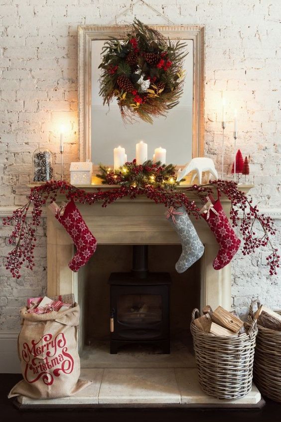Christmas decor done with baskets, with pillar candles, evergreens, pinecones, red berries and red and grey printed Christmas stockings