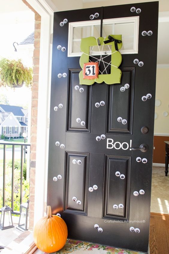 a Halloween front door covered with googly eyes, a neon green wreath and a pumpkin is a very bold and fun idea