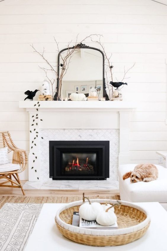 a Halloween mantel with blackbirds, spiders, branches, white pumpkins, a mirror in a black frame is all cool