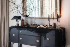 a beautiful black credenza decorated with black spider web, blackbirds, black candles and black branches is amazing