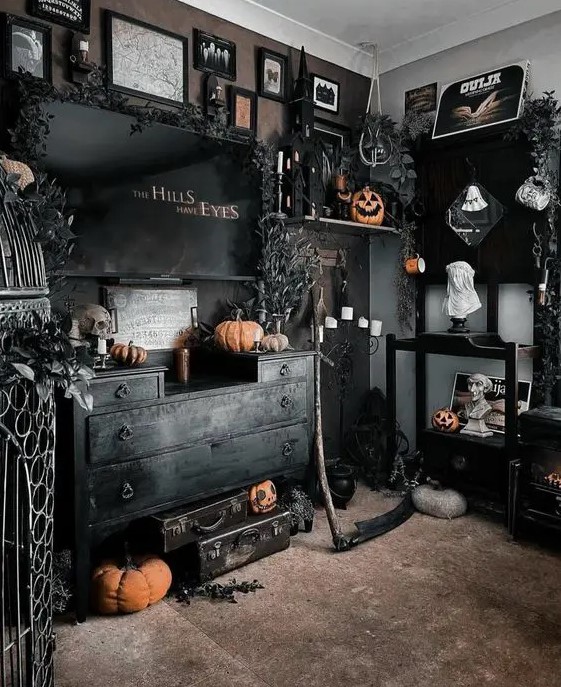 a black Halloween room with a catchy gallery wall, black suitcases, orange pumpkins and black blooms and leaves