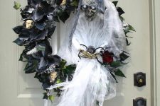 a black faux leaf and flower wreath with skulls, a ghost with a bloom is a very statement-like and bold idea for Halloween