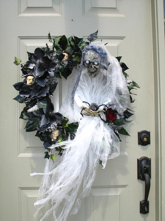 a black faux leaf and flower wreath with skulls, a ghost with a bloom is a very statement-like and bold idea for Halloween