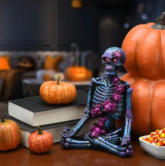 a black meditating skeleton covered with purple spiders is a cool and bold idea to decorate your space for Halloween