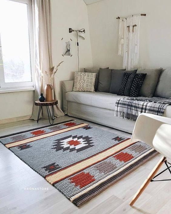 a boho living room accented with a grey, red and tan printed rug that makes it cool and bold and gives personality to it