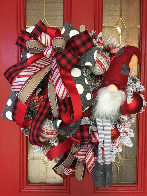 a bold and catchy red and white Christmas wreath with lots of burlap, red, white and grey ribbons, red and white ornaments, a large gnome in a red hat
