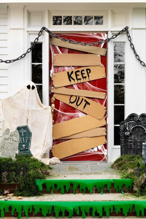 a bold and outstanding Halloween front porch with a scary door with signs and chains, tombstones and black drip on the steps