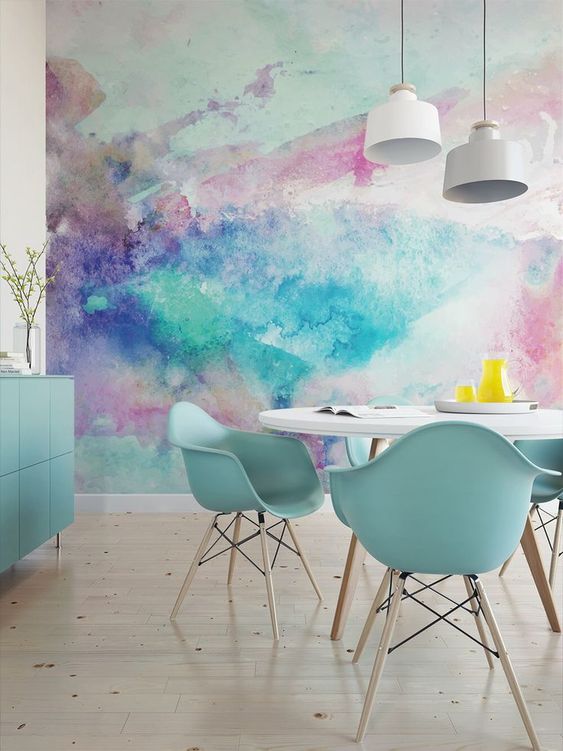 a bright dining space with a colorful watercolor wall mural and mint blue furniture to echo it and make the space cohesive