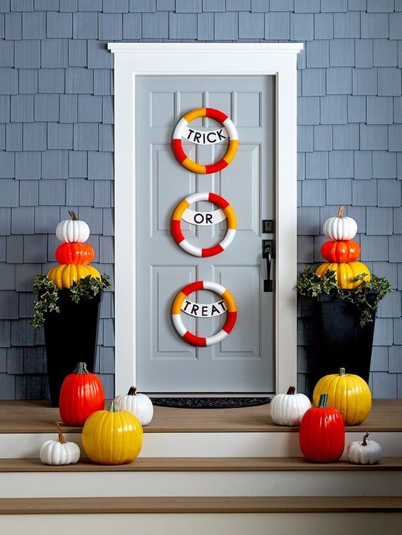 a colorful Halloween porch with colorful mini wreaths, colorful pumpkins on the steps and in the planters