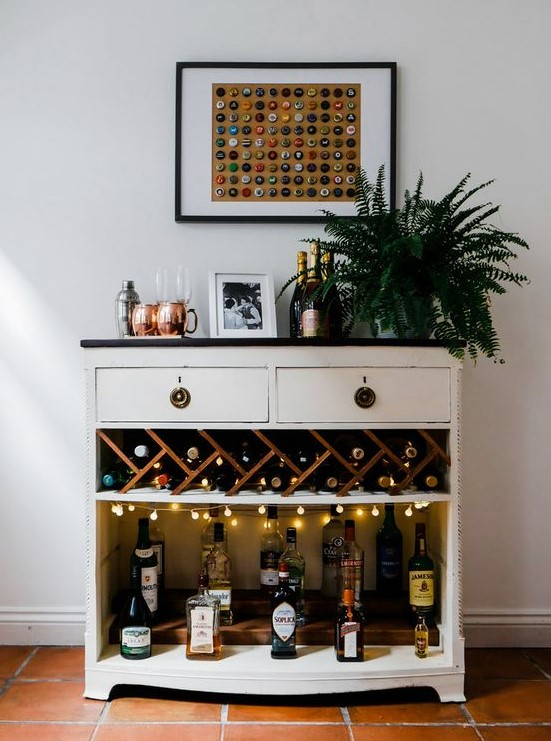 a cool bar unit with open space with lights, drawers and a potted plant plus a catchy artwork of lids